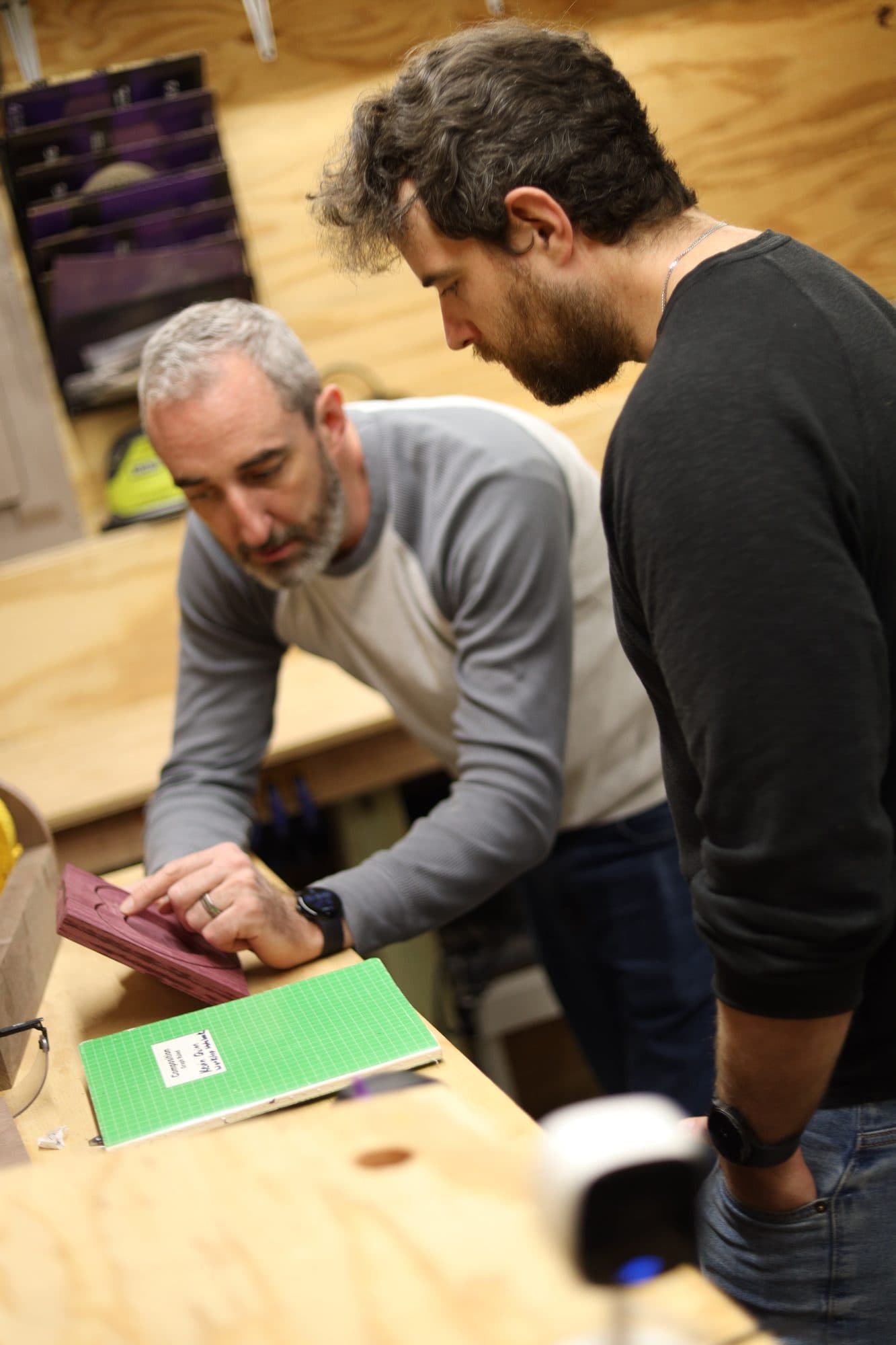Two woodworkers in the Quinn Woodcrafting shop comparing a piece of hardwood